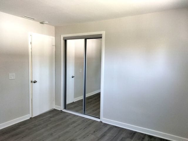 unfurnished bedroom featuring dark hardwood / wood-style flooring and a closet