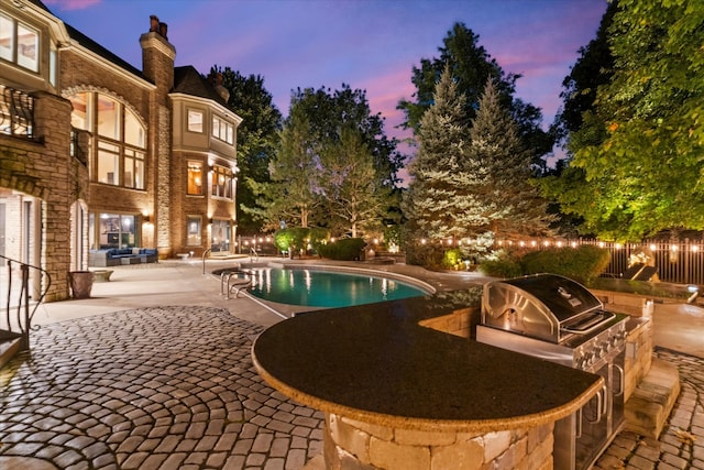 pool at dusk featuring area for grilling and a patio