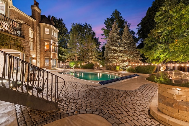 pool at dusk featuring a patio area