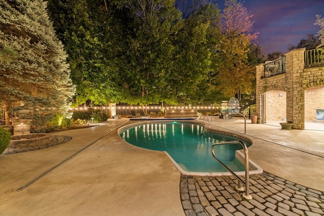 pool at dusk with a patio area