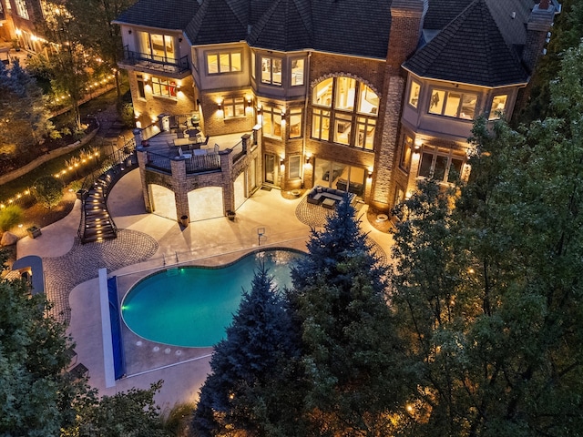 back house at night with a balcony, a patio, and an outdoor hangout area