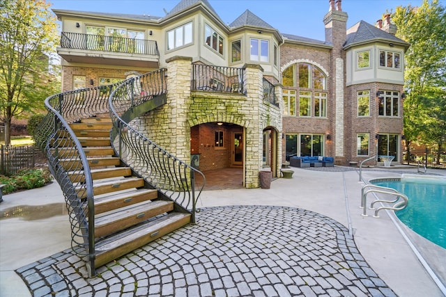 back of house featuring a balcony, a fenced in pool, and a patio area