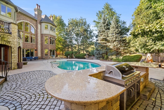 view of pool featuring exterior kitchen and a patio area