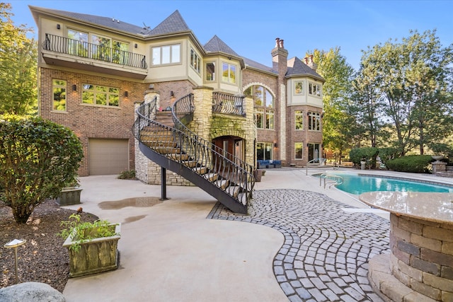 back of property featuring a garage, a patio, and a balcony