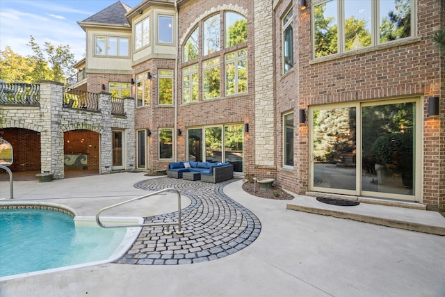 rear view of house featuring a balcony, an outdoor living space, and a patio area