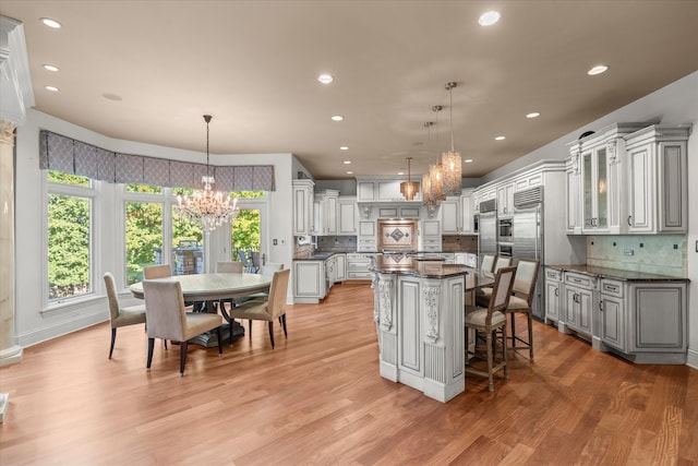 kitchen with hanging light fixtures, built in refrigerator, decorative backsplash, and a center island