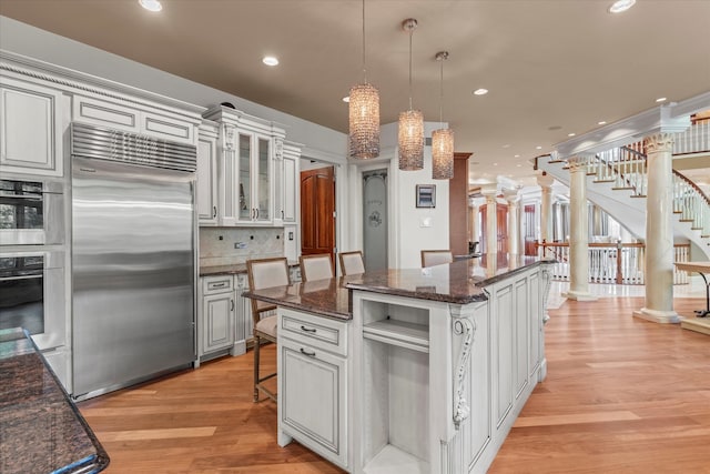 kitchen featuring stainless steel built in fridge, light hardwood / wood-style floors, a center island, decorative backsplash, and white cabinetry