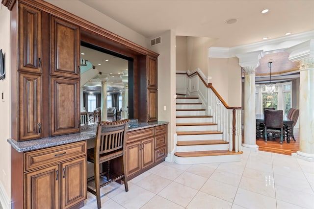 interior space with tile patterned floors, ornamental molding, vanity, decorative columns, and a chandelier