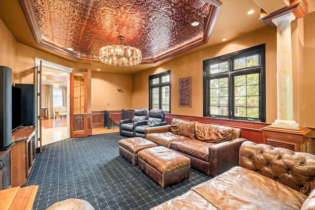 living room with ornamental molding, a raised ceiling, a notable chandelier, and decorative columns