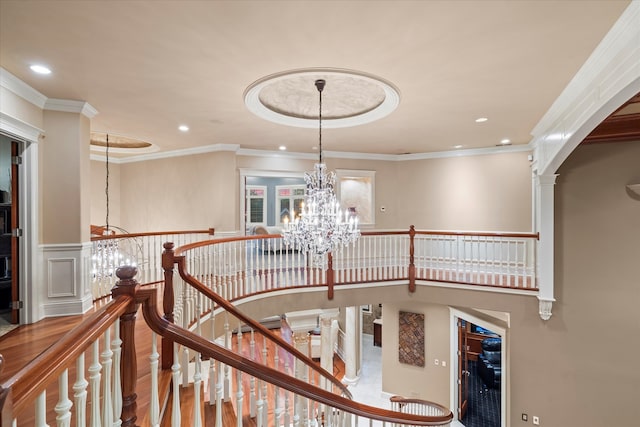 staircase with hardwood / wood-style flooring, a chandelier, crown molding, and decorative columns