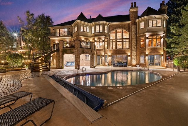 back house at dusk with a patio and a balcony