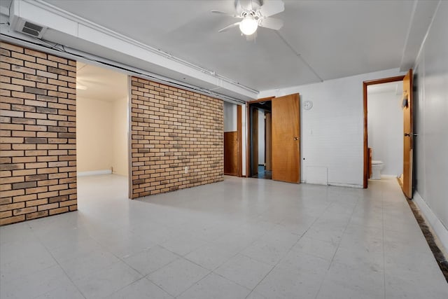 unfurnished room with ceiling fan and brick wall