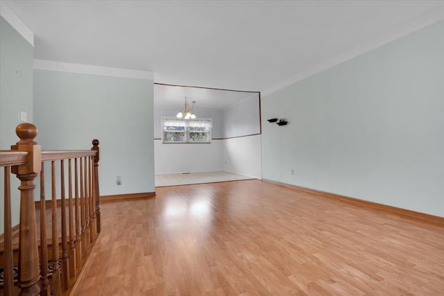 spare room featuring an inviting chandelier, light hardwood / wood-style flooring, and crown molding