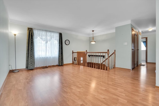 spare room with ornamental molding, light hardwood / wood-style floors, and a healthy amount of sunlight