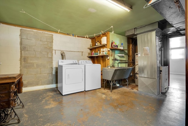 laundry area with heating unit, separate washer and dryer, and sink