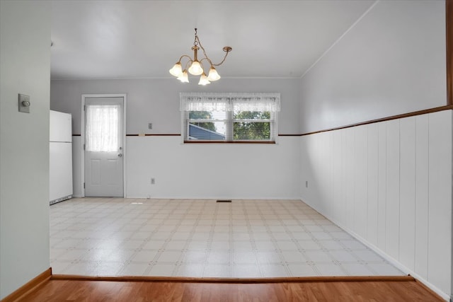 empty room featuring light wood-type flooring, a chandelier, plenty of natural light, and crown molding