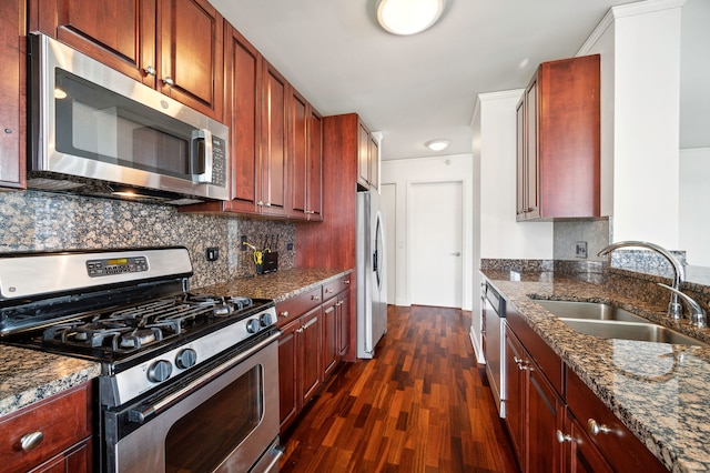 kitchen with dark hardwood / wood-style floors, dark stone countertops, sink, and stainless steel appliances