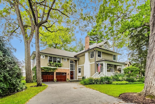 view of front of property featuring brick siding, a garage, a front yard, a chimney, and driveway