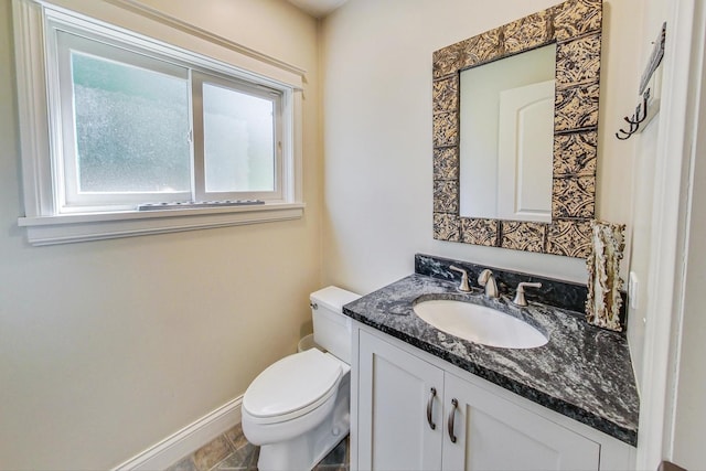 half bathroom featuring toilet, baseboards, and vanity