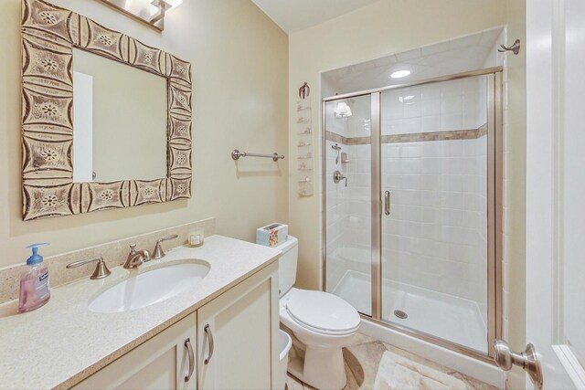 full bathroom featuring vanity, a shower stall, and toilet