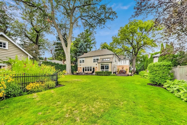 back of property featuring fence, a yard, and a wooden deck