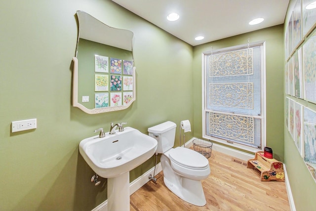 bathroom featuring visible vents, baseboards, wood finished floors, and toilet