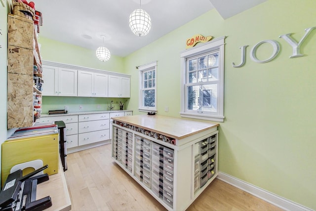 611 Elmwood Ave, Wilmette, IL 60091 - kitchen with white cabinets, light wood-style floors, light countertops, and decorative light fixtures