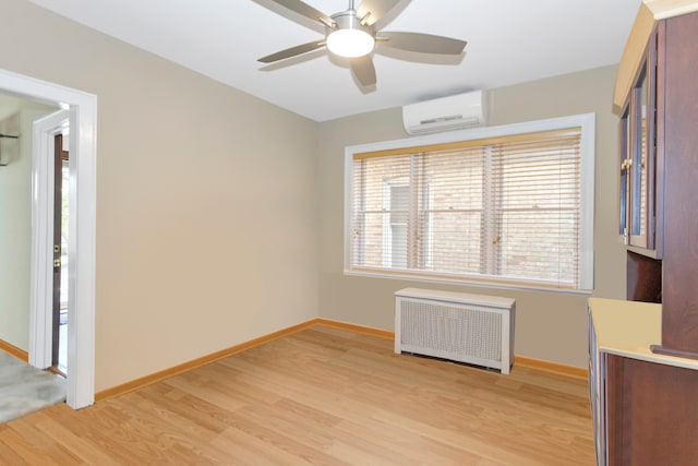 empty room with an AC wall unit, radiator, light wood-type flooring, and ceiling fan