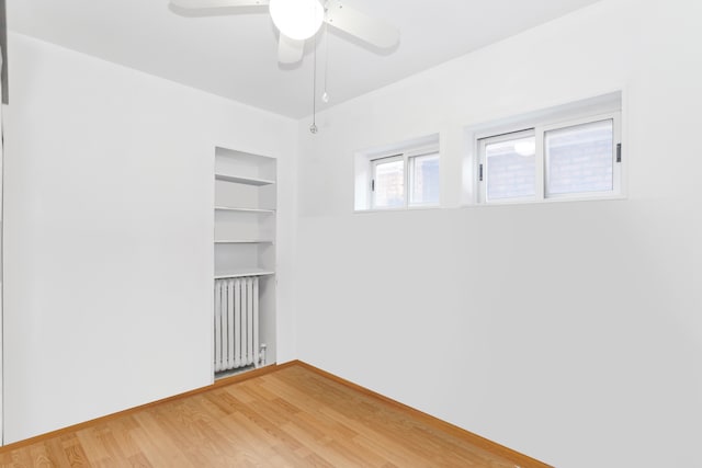 empty room with radiator heating unit, wood-type flooring, and ceiling fan