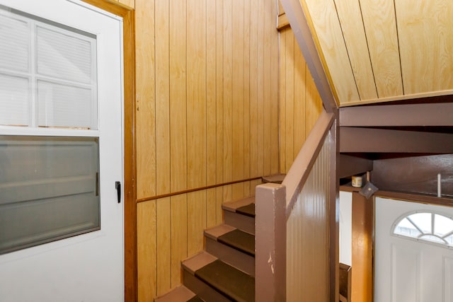 stairway featuring wooden walls