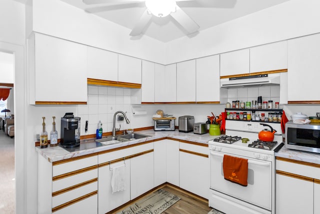 kitchen with white gas range oven, sink, and white cabinets