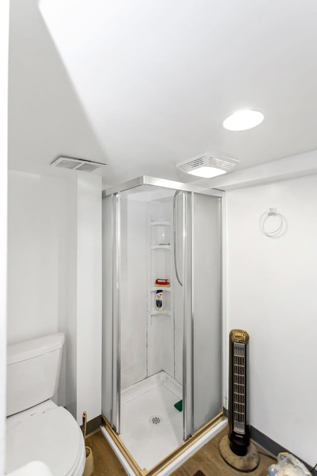 bathroom with toilet and a shower with shower door