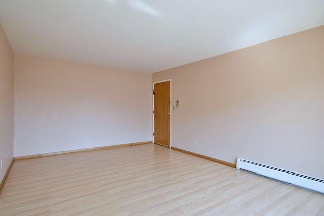 unfurnished room with a baseboard heating unit and light hardwood / wood-style floors