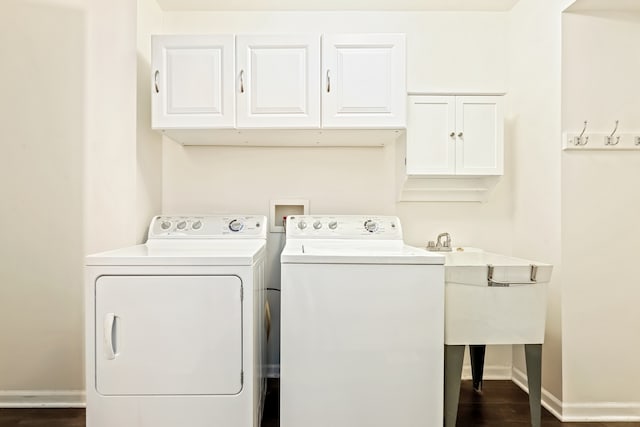 washroom featuring cabinets, sink, washer and clothes dryer, and dark hardwood / wood-style flooring