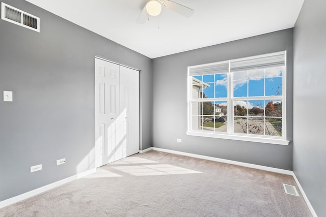 unfurnished bedroom with light carpet, a closet, and ceiling fan