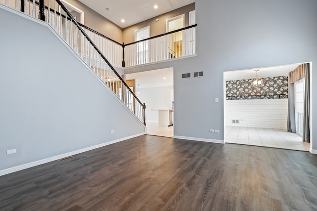 unfurnished living room with hardwood / wood-style flooring and a towering ceiling