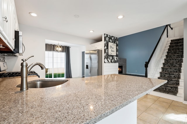 kitchen with hanging light fixtures, stainless steel appliances, light stone countertops, light tile patterned floors, and white cabinets