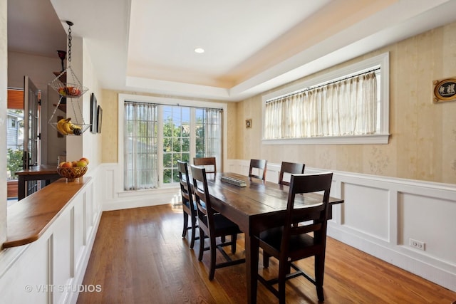 dining space with hardwood / wood-style floors and a tray ceiling