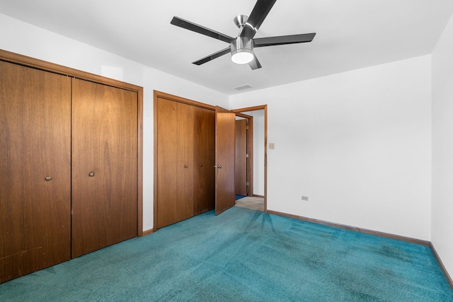 unfurnished bedroom with ceiling fan, light colored carpet, and multiple closets