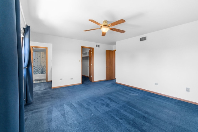 unfurnished bedroom featuring dark colored carpet, ceiling fan, a walk in closet, and a closet