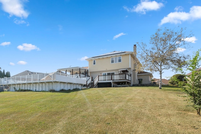 rear view of property featuring a lawn and a deck