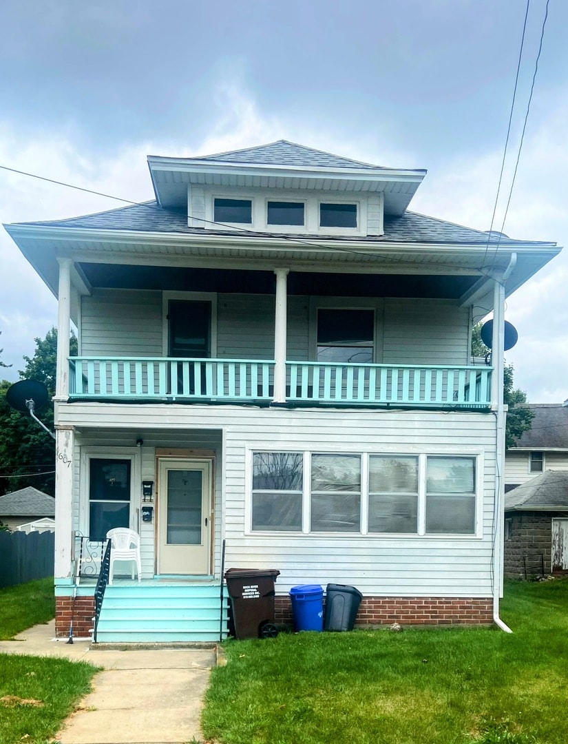 back of house featuring a balcony and a yard