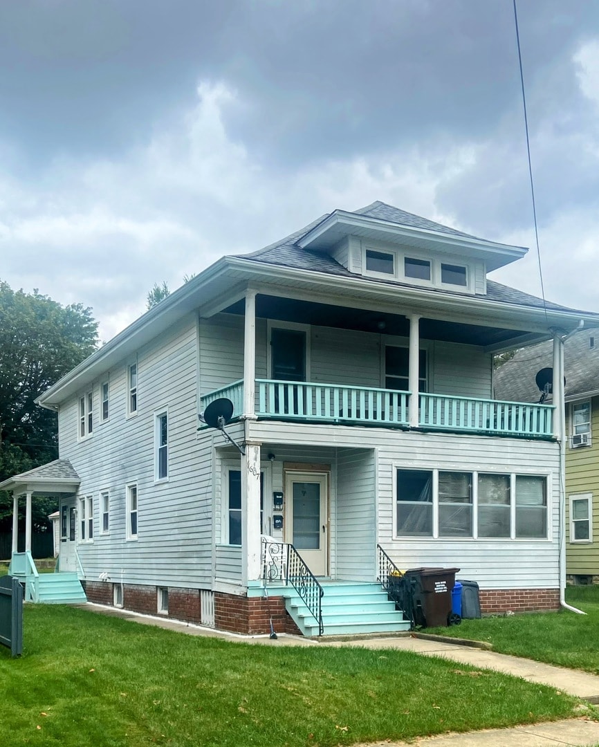 rear view of property featuring a balcony and a yard