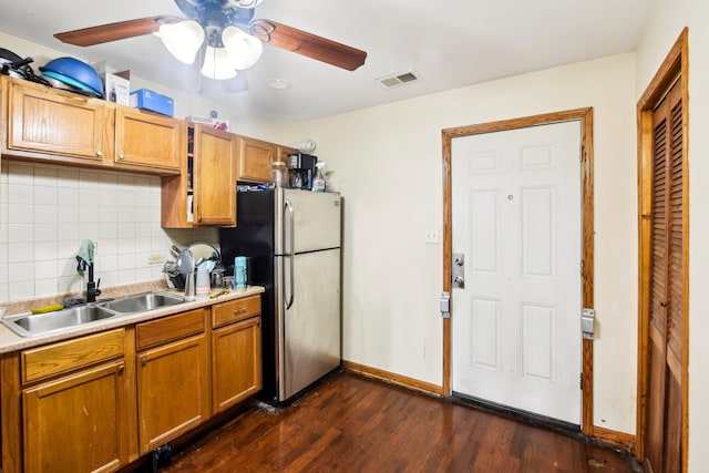 kitchen with dark wood-type flooring, tasteful backsplash, stainless steel refrigerator, ceiling fan, and sink