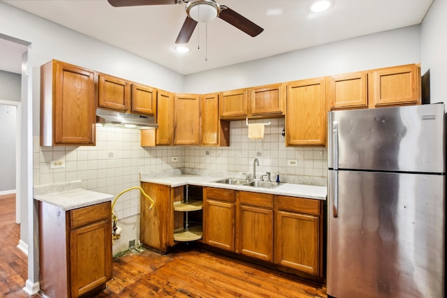 kitchen featuring dark wood-type flooring, sink, backsplash, ceiling fan, and stainless steel fridge