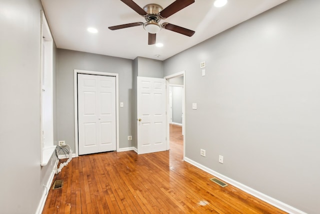 unfurnished bedroom featuring ceiling fan, hardwood / wood-style flooring, and a closet