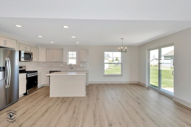 kitchen featuring appliances with stainless steel finishes, pendant lighting, plenty of natural light, and white cabinets