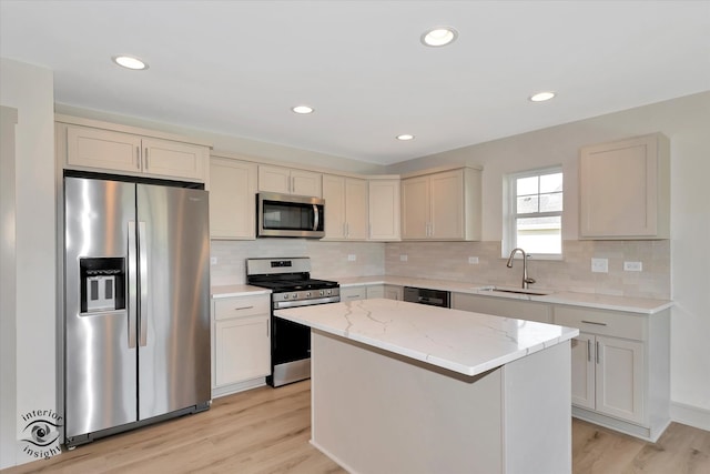 kitchen with stainless steel appliances, light wood-type flooring, sink, and a center island