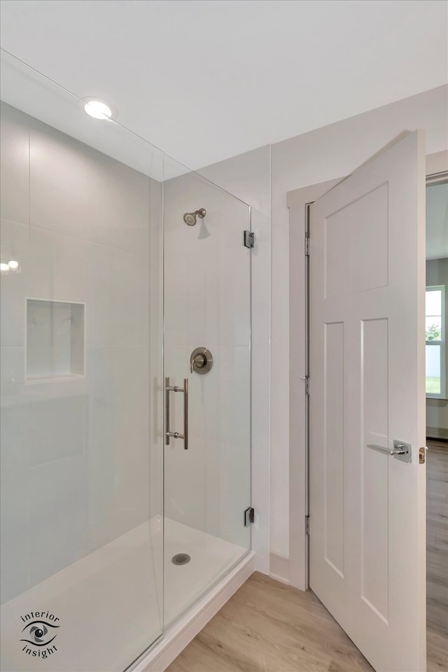 bathroom with an enclosed shower and wood-type flooring