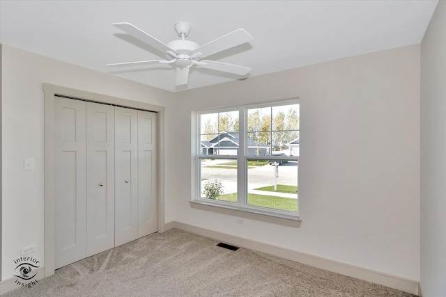 unfurnished bedroom featuring ceiling fan, a closet, and light carpet